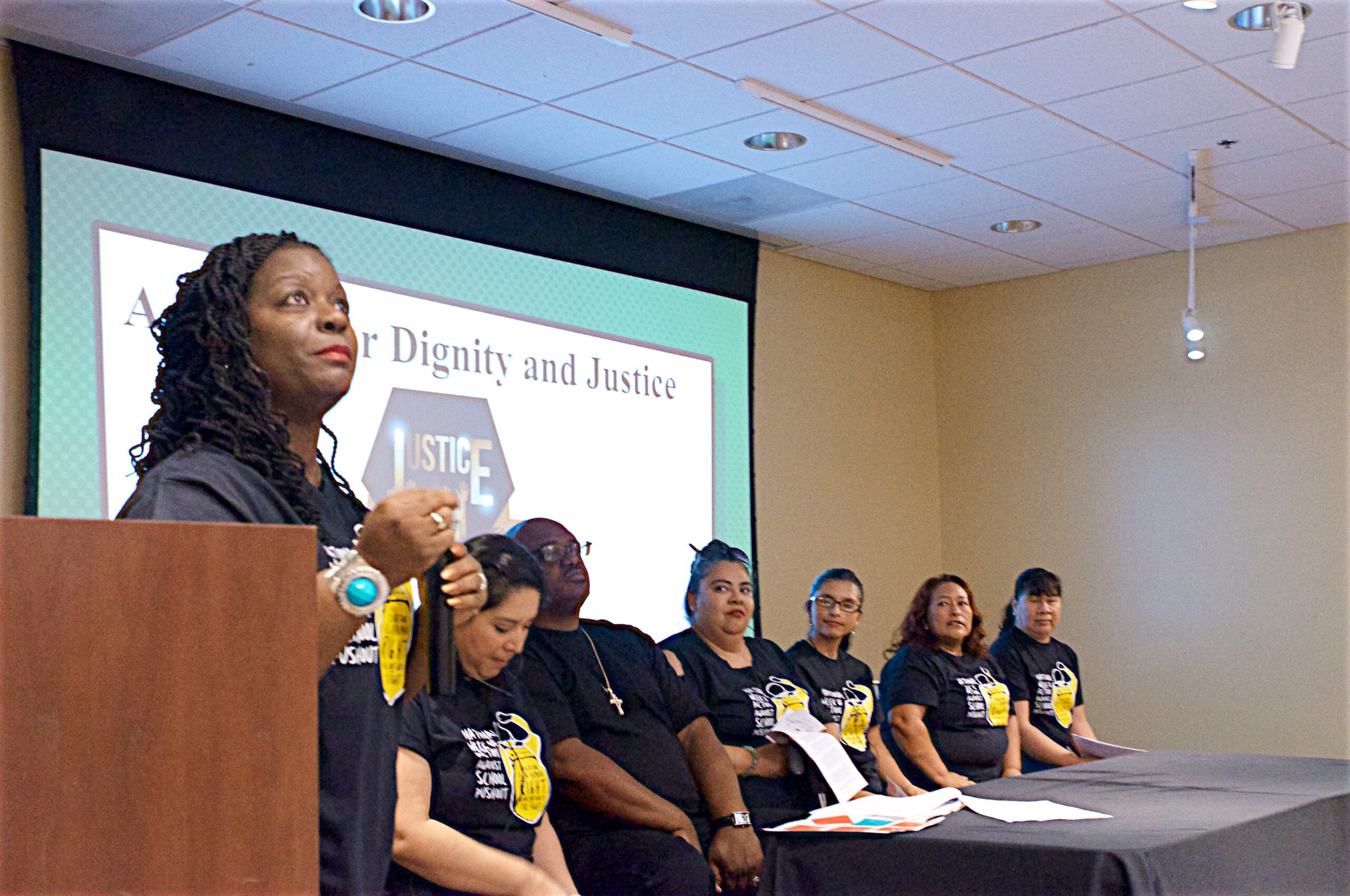 CADRE parent leader speaking at a community forum with other parent leaders on stage